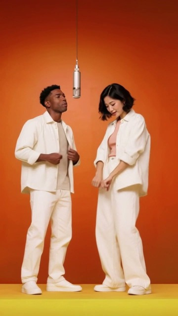 Frame from the tested Hotel Lobby template: two generated adults in light clothing in an orange studio